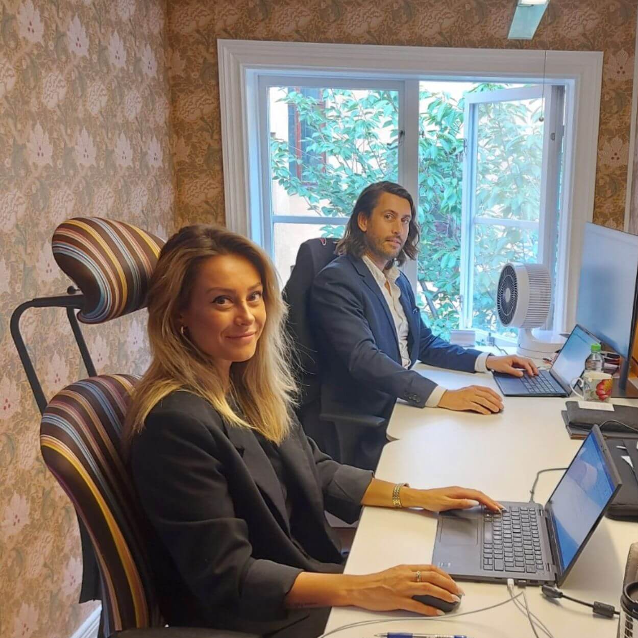 två dynamicskonsulter som jobbar med varsin laptop framför ett fönster